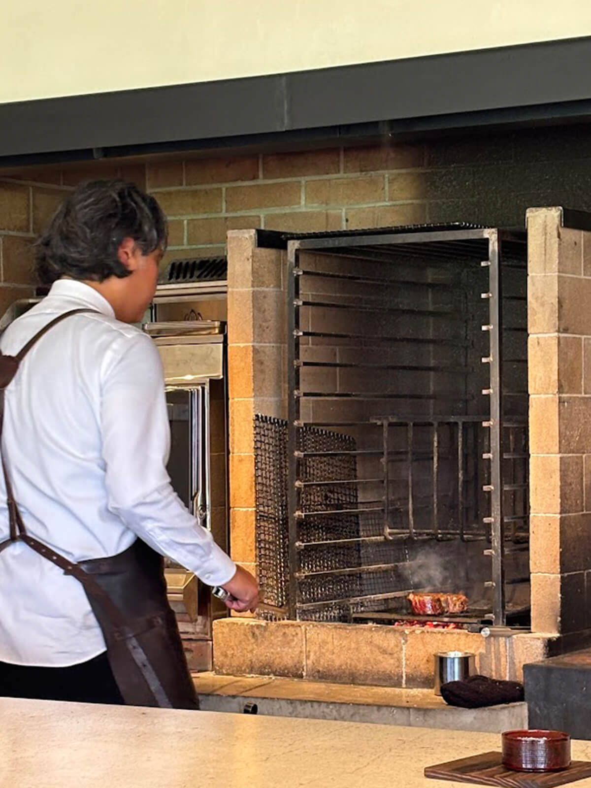 丁寧に肉を焼く長屋恭平シェフの画像