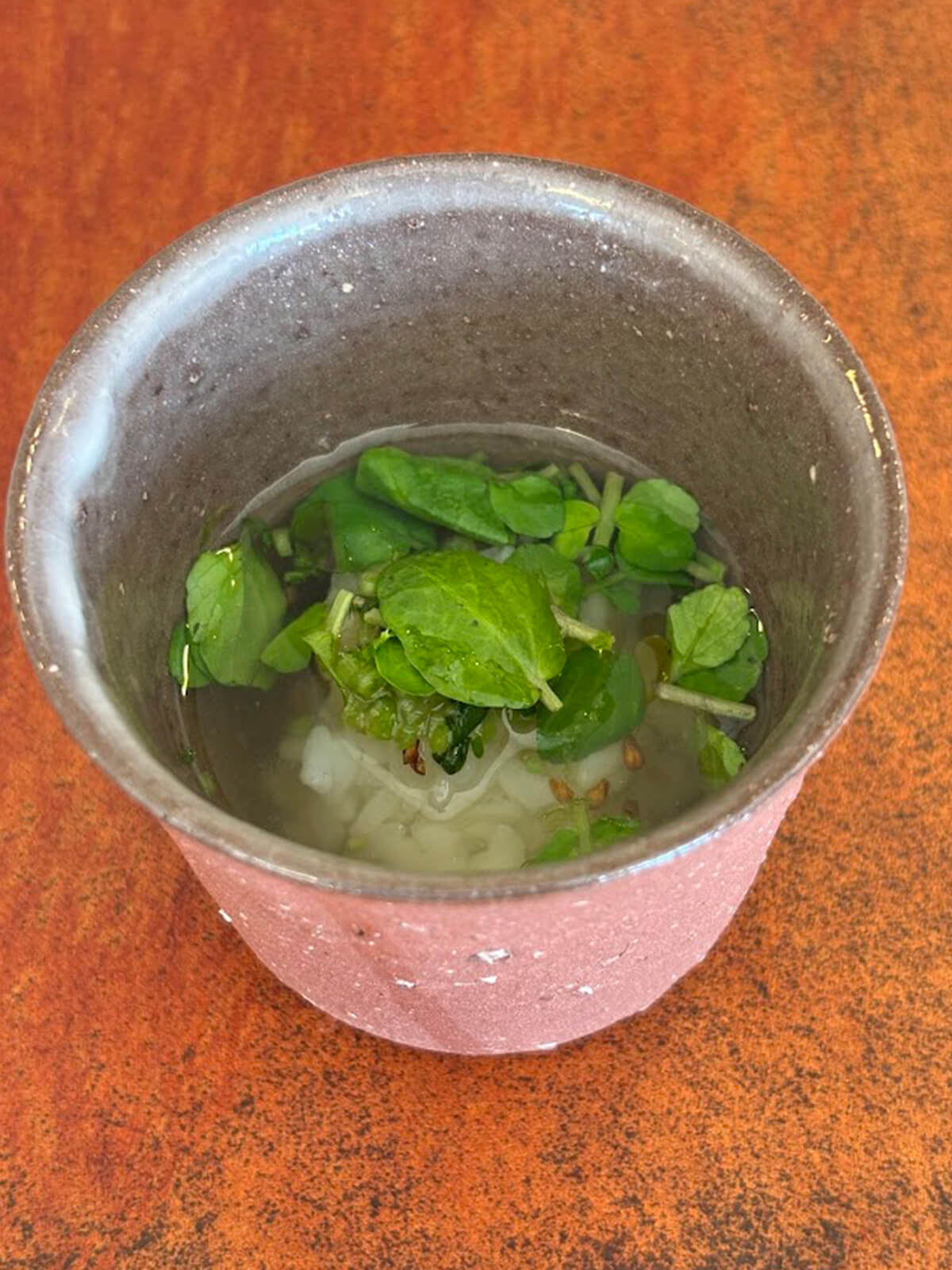 スープ仕立てのご飯に、生クレソンが添えられている画像