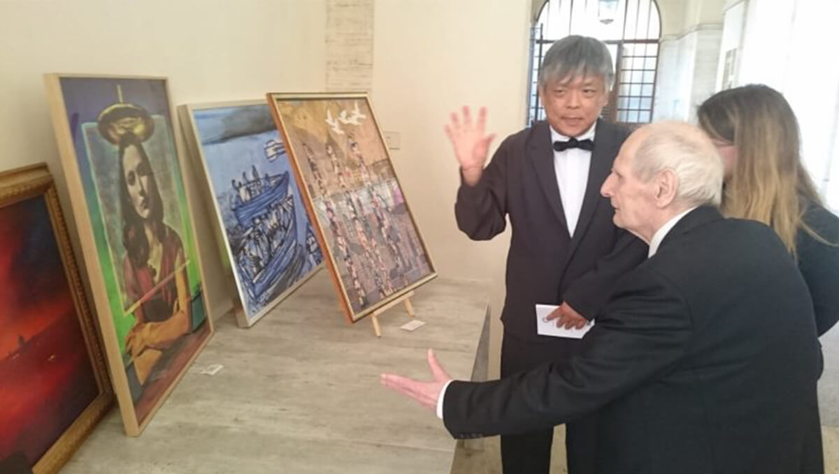 フランチェスコ・コッコパルメリオ枢機卿立法文書省名誉長官に、カリタ・ポルティカ財団に寄贈した作品を説明している画像