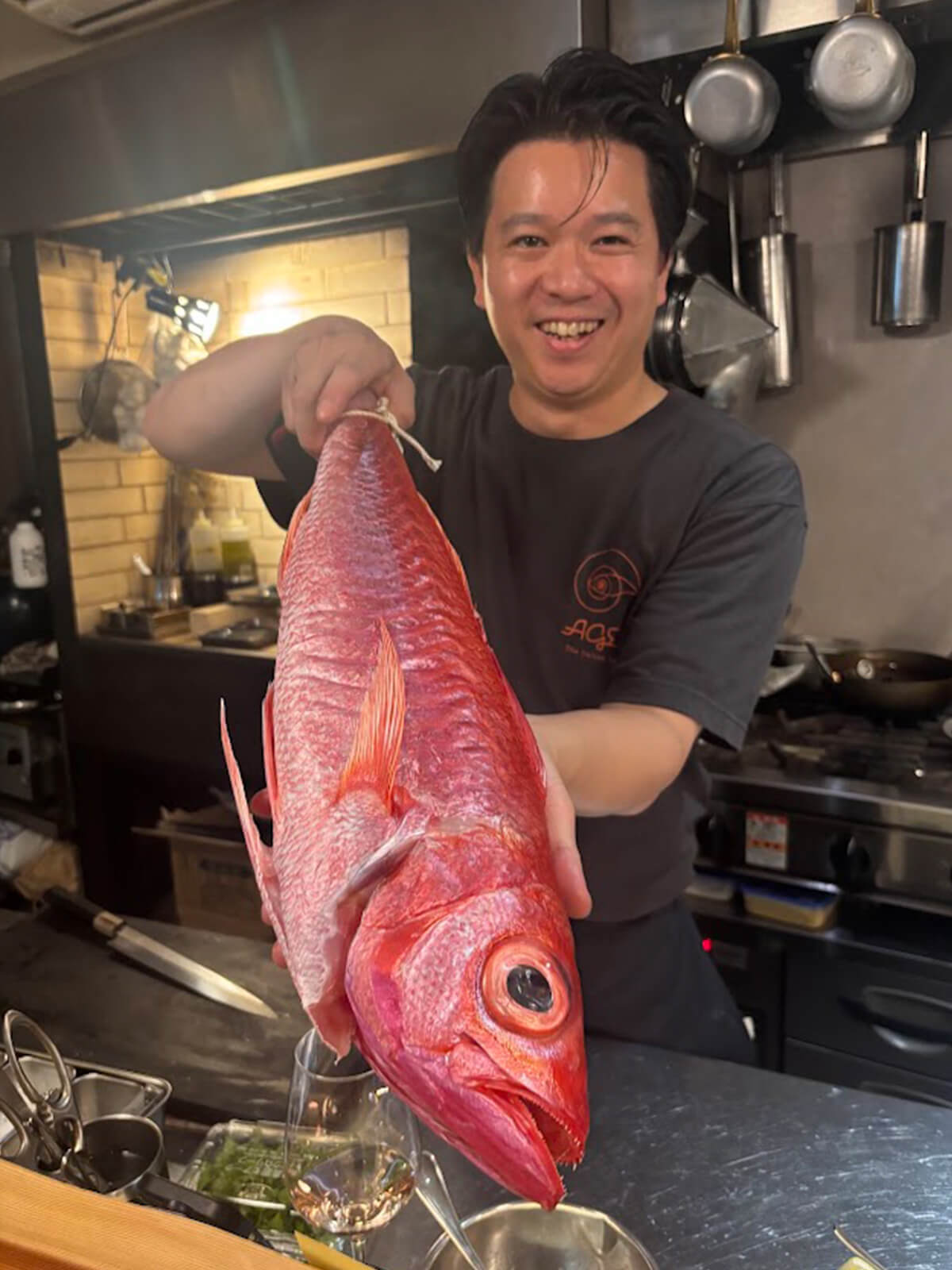 奄美大島の尾長鯛を持つ島田シェフの画像